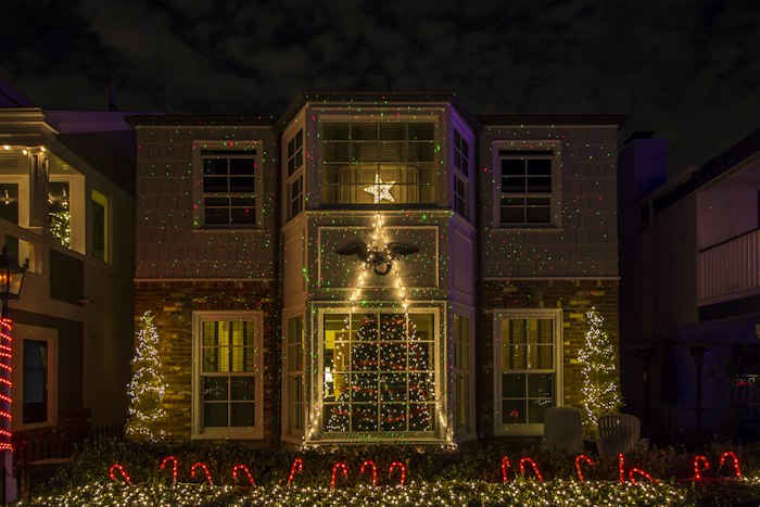 Two-story home with warm white Christmas lighting and lit trees